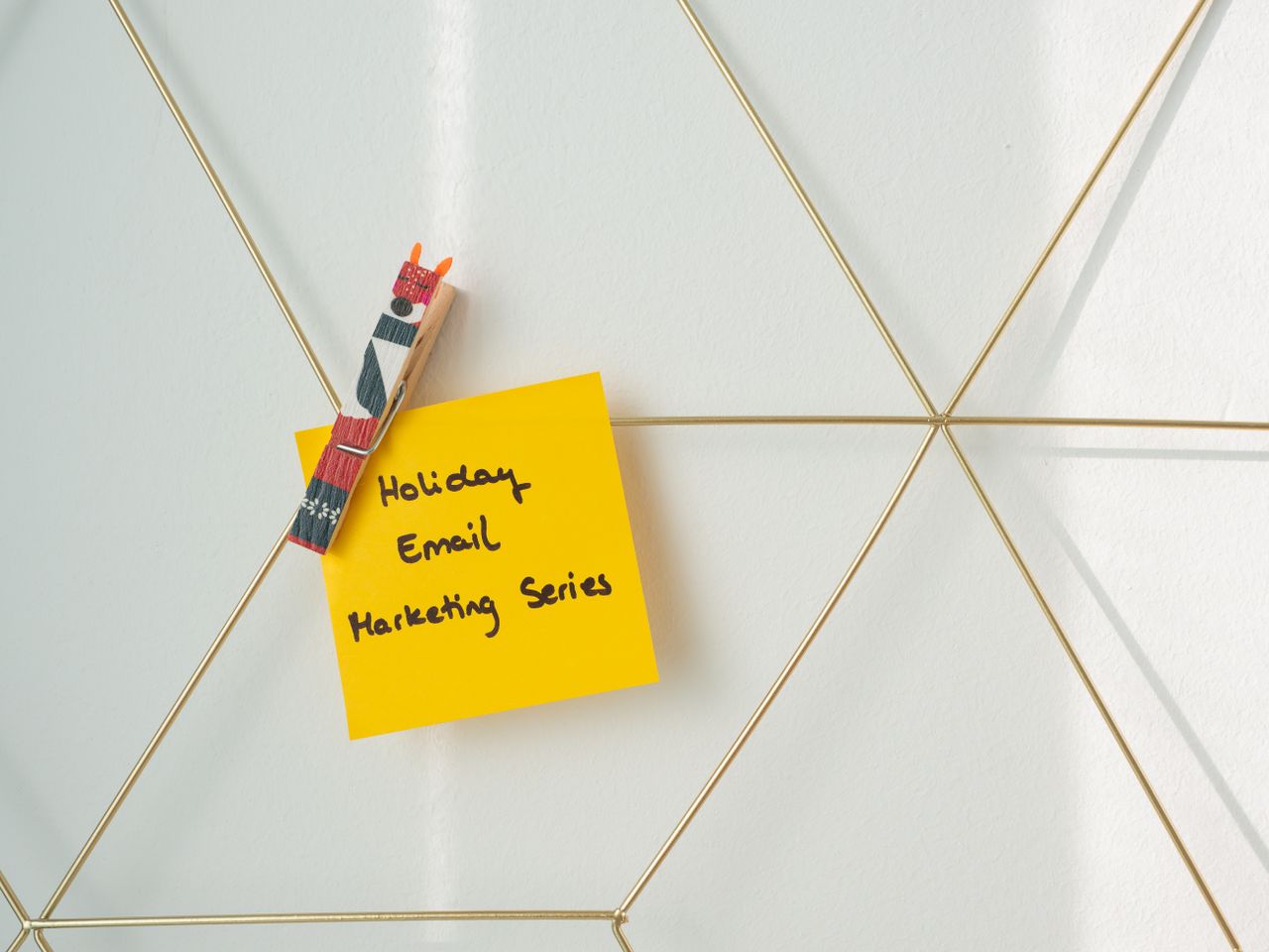 Post-it jaune vif avec un message de marketing par e-mail pour les fêtes, fixé à un mur de maquette filaire.